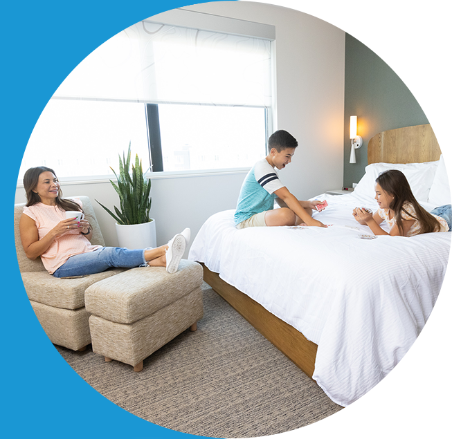 A family laying in bed in a hotel room.