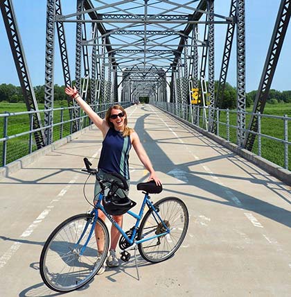 A woman bicycling on a bridge.
