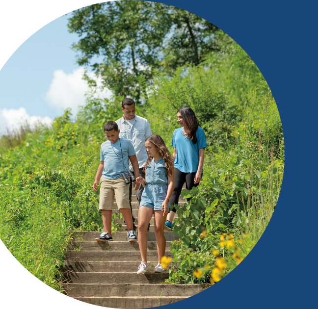 A family walking down some steps in a lush outdoor park.