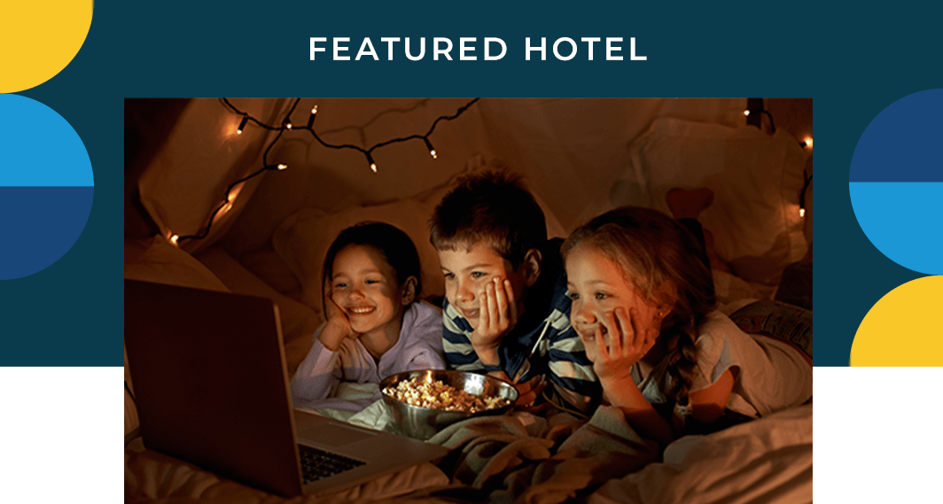 Featured Hotel - A group of children watching television on a laptop in a fort.